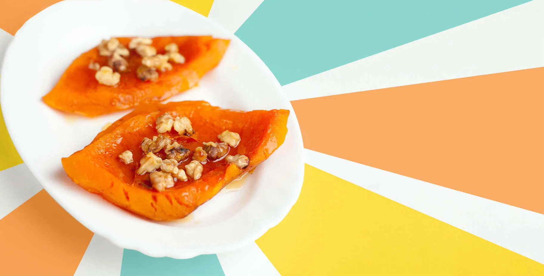 2 pieces of pumpkin with little pieces of walnuts on top, on a white plate. Diabeloop background of orange, yellow and turquoise rays.